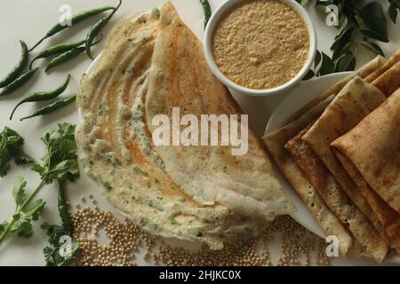 Jowar Dosa. Ein herzhaftes Crepe aus Jowar-Mehl. Goldene knusprige Dosa aus Jowarmehl, Zwiebeln, Kreuzkümmel, Ingwer, grünem Chili und Cor Stockfoto