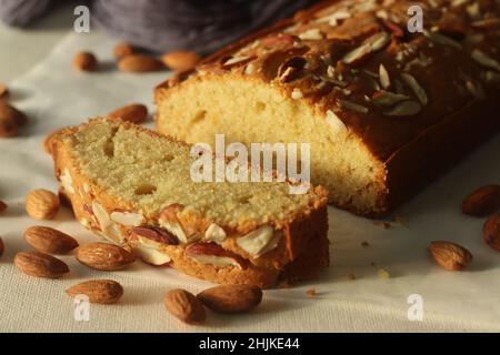 Ghee-Kuchenscheibe. Ghee-Kuchen mit Vanillegeschmack und Mandeln darauf. Der perfekte Begleiter für eine Tasse Kaffee. Aufgenommen auf weißem Hintergrund Stockfoto