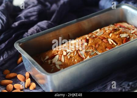 Ghee-Kuchen in der Brotform. Ghee-Kuchen mit Vanillegeschmack und Mandeln darauf. Der perfekte Begleiter für eine Tasse Kaffee. Aufgenommen auf weißem Hintergrund Stockfoto