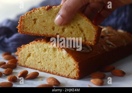 Ghee-Kuchenscheibe. Ghee-Kuchen mit Vanillegeschmack und Mandeln darauf. Der perfekte Begleiter für eine Tasse Kaffee. Aufgenommen auf weißem Hintergrund Stockfoto