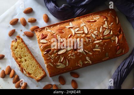 Ghee-Kuchenscheibe. Ghee-Kuchen mit Vanillegeschmack und Mandeln darauf. Der perfekte Begleiter für eine Tasse Kaffee. Aufgenommen auf weißem Hintergrund Stockfoto