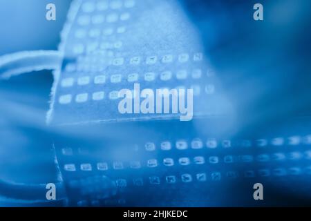 Abstrakte kreative Komposition der OP-Maske in tiefen ultramarinen Farben auf einer reflektierenden Oberfläche platziert. Stockfoto