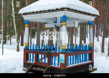 Das blau-weiße Kruzifix ist in einem Winterwald mit Schnee bedeckt Stockfoto