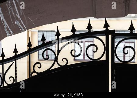 Altes schwarz geschmiedetes Metalltor-Fragment, Nahaufnahme mit selektivem Fokus. Klassische Architektur der Sankt-Petersburger Altstadt, Russland Stockfoto