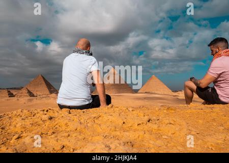 Zwei Männer Reisende posieren vor den großen Pyramiden von gizeh in kairo ägypten. Reisen ägypten im Winter, kalten Winter bedeckt Tag. Stockfoto