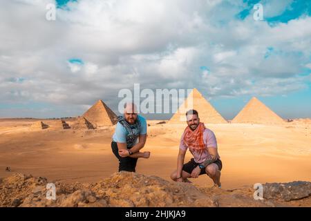 Zwei Männer Reisende posieren vor den großen Pyramiden von gizeh in kairo ägypten. Reisen ägypten im Winter, kalten Winter bedeckt Tag. Stockfoto