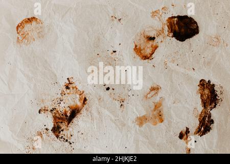 Ein unordentliches Backpapier, nachdem man Süßkartoffeln darauf gebacken hat. Viele abstrakte Details. Flach liegend, Draufsicht. Dunkle verbrannte Flecken karamellisierten Zuckers. Stockfoto