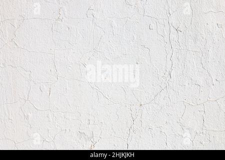 Wand mit Zement verputzt und mit weißer Farbe bemalt. Die Textur von Rissen und Unvollkommenheiten ist zu sehen. Stockfoto