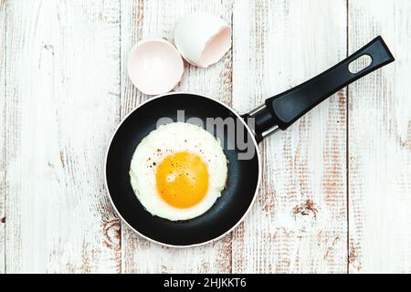 Spiegeleier in einer Pfanne auf einem hölzernen Hintergrund. Traditionelles englisches Frühstück. Hintergrund der Speisen. Stockfoto