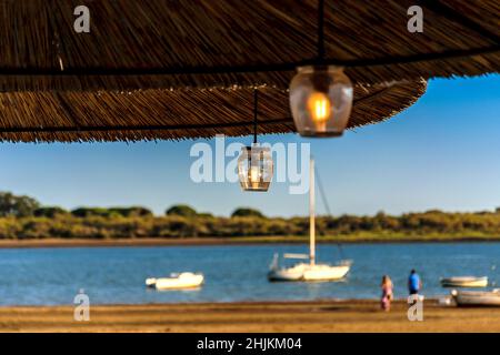 Von einem Strohschirm hängt eine Laterne in den frühen Morgenstunden des Sonnenuntergangs Stockfoto
