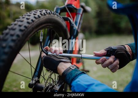 Mann pumpt Fahrrad Rad im Park. Der Mann pumpt das Rad mit einer Pumpe auf.  Pumpen von Luft in ein leeres Rad des Fahrrads Stockfotografie - Alamy