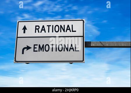 Straßenschild mit Worten rational und emotional. Weiße zwei Straßenschilder mit Pfeil auf Metallmast auf blauem Himmel Hintergrund. Stockfoto