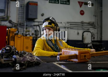 PAZIFISCHER OZEAN (Jan 16, 2022) Aviation Boatswain's Mate (Handling) 2nd Class Ciaira Meyers, aus West Palm Beach, Florida, betreibt einen Traktor in der Hangarbucht an Bord der USS Abraham Lincoln (CVN 72). Die Abraham Lincoln Strike Group befindet sich im geplanten Einsatzgebiet der US-Flotte für 7th, um die Interoperabilität durch Allianzen und Partnerschaften zu verbessern und gleichzeitig als reaktionsfähige Truppe zur Unterstützung einer freien und offenen Region im Indo-Pazifik-Raum zu dienen. Stockfoto