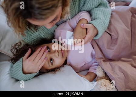 Mutter, die sich zu Hause um ihre kranke Tochter kümmert. Stockfoto
