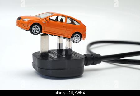 MODELLAUTO AUF ELEKTRISCHEN STECKER UND BLEI RE ELEKTROAUTOS FAHRZEUG EV NULL EMISSIONEN GRÜN MOTORING BENZIN DIESEL FOSSILEN BRENNSTOFF ETC UK Stockfoto