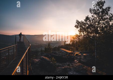 Mann, der auf einem neuen und modernen Aussichtspark steht The Guard Patrol, Tschechisch: Straz, beim Sonnenaufgang, Sonnenaufgang auf dem Straznik-Hügel oberhalb von Rokytnice Stockfoto