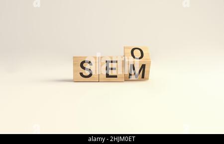 SEO vs. SEM. Holzwürfelblock Flip über Wort SEO zu SEM auf Yellow Studio Hintergrund. 3D Abbildung. Stockfoto