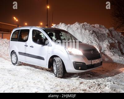 Moskau. Russland. 29. Januar 2022. Silberner Minivan Opel Combo Life vor dem Hintergrund riesiger Schneehaufen in einer Winternacht. Stockfoto