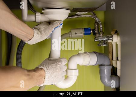Männliche Hände drehen das Ablaufrohr unter dem Waschbecken in der Küche. Hochwertige Fotos Stockfoto