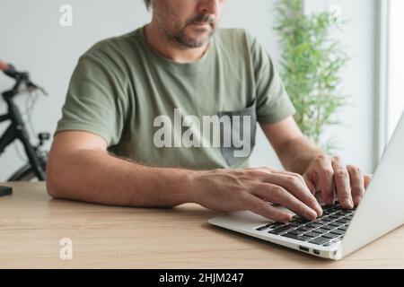 Telearbeiter, der die Tastatur eines Laptops im Home Office während der Arbeit an entfernten Standorten eingibt, selektiver Fokus Stockfoto