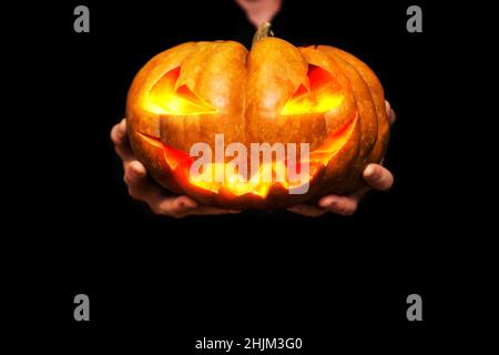Halloween. Der Mann hält in den Händen geschnitzten halloween-Kürbis auf schwarzem Hintergrund. Speicherplatz kopieren. Stockfoto