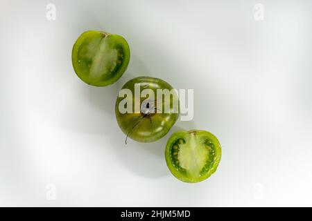 Drei grüne Tomaten isoliert auf weißem Hintergrund. Gesundes Essen und veganes Rohkost-Konzept, kreatives Flat-Lay. Text kopieren Stockfoto