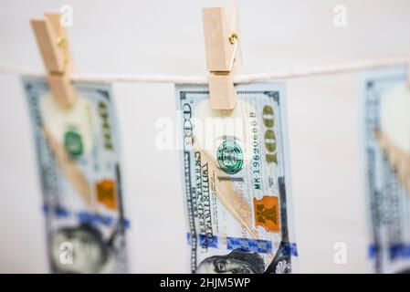 Amerikanische 100-Dollar-Scheine hängen an einem Seil mit hölzernen Wäscheklammern. Geldwäsche-Konzept. Schmutziges Geld. Stockfoto