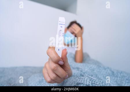 Kranke infizierte Frau, die einen schnellen Covid-Antigen-Test oder einen Express-Covid-Test mit positivem Ergebnis zeigt. Frau mit Coronavirus-Infektion Stockfoto