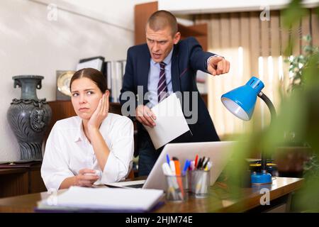 Ein junger Geschäftsmann schimpft sein Mädchen im Büro Stockfoto