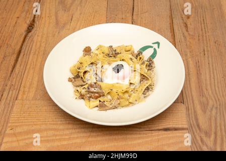 Frische Pasta 100 % italienischer Herkunft, mit schwarzer Trüffelcreme, Ei bei niedriger Temperatur, Champignons in Scheiben und geriebenem Parmesan Stockfoto