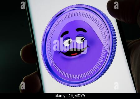 McDonalds Grimace Coin auf dem Smartphone-Bildschirm gesehen in den Händen halten. Gefälschte Meme-Münze. Stafford, Großbritannien, 30. Januar 2022. Stockfoto