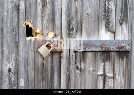 Altes Holztor mit Beschädigungen und rostigen Bolzen und Vorhängeschloss Stockfoto