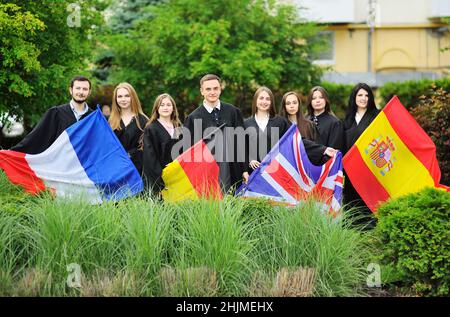 Eine Gruppe von Studenten der Fakultät für Fremdsprachen, die in Gewändern studieren, halten die Flaggen Großbritanniens, Frankreichs, Spaniens und Deutschlands in den Händen. Stockfoto