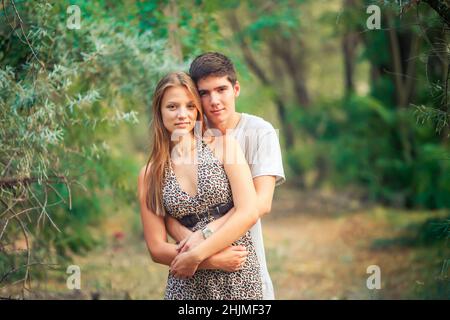 Der junge Mann umarmt seine Geliebte, die hinter ihr steht. Ein glückliches Paar in der Liebe verbringt Zeit zusammen in der Natur Stockfoto