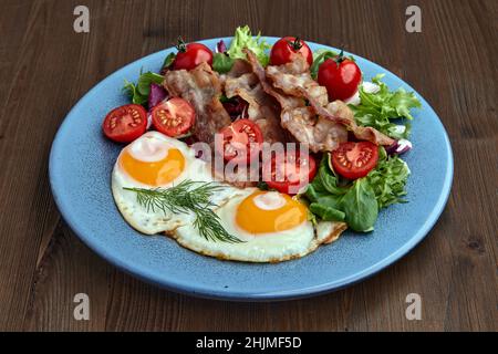 Spiegeleier mit Speck, Salat und Kirschtomaten Stockfoto