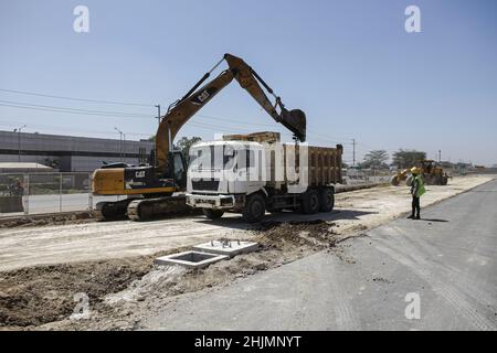 Nairobi, Kenia. 26th Januar 2022. Ein Bagger belädt einen LKW auf einem Abschnitt einer Baustelle des Nairobi Expressway Project entlang der Mombasa Road. Der Bau der 27,1km langen mautpflichtigen Autobahn, der Nairobi Expressway, wird fortgesetzt und soll im Juni 2022 abgeschlossen werden. Der Nairobi Expressway soll die Stadt Nairobi durch einen schnelleren und zuverlässigen Transport entlasten. Kredit: SOPA Images Limited/Alamy Live Nachrichten Stockfoto