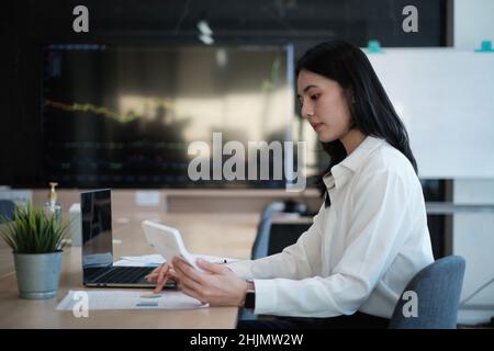 Eine Geschäftsfrau, Buchhalterin oder Bankkauffrau, führt eine Prüfung durch und berechnet die Ausgaben für eine Bilanzrechnung eines Finanzberichts mithilfe eines Rechners. Der Stockfoto