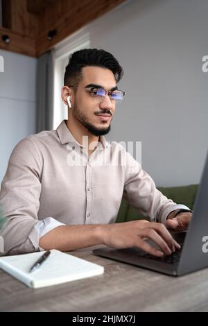 Glücklicher junger Mann Student studieren oder arbeiten online auf Laptop aus dem Heimbüro Stockfoto