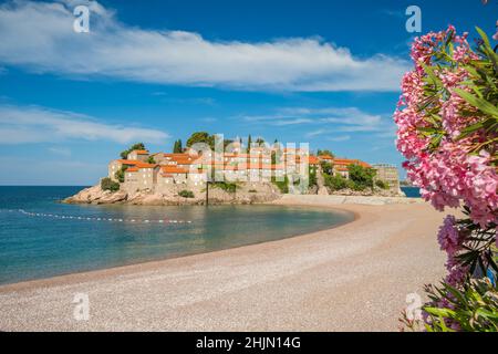 Schöner leerer Strand und Insel Sveti Stefan am sonnigen Sommertag in Montenegro Stockfoto