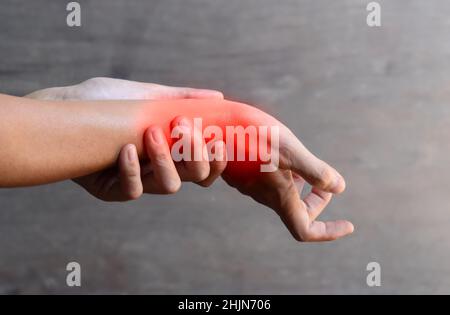 Entzündung des asiatischen jungen Mannes Handgelenk und Hand. Konzept von Gelenkschmerzen und Handproblemen. Stockfoto