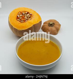 Eine Schüssel mit Kürbiscremesuppe (vellutata di zucca) isoliert auf weißem Hintergrund. Stockfoto