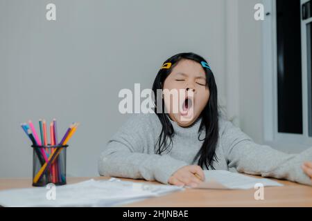 Asiatische Mädchen gähnend während der Arbeit auf einem Schreibtisch Stockfoto