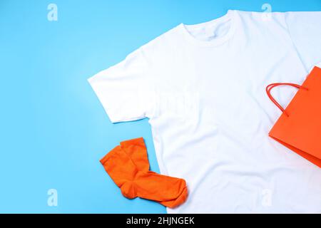 Leeres T-Shirt, Tasche und Socken auf blauem Hintergrund Stockfoto