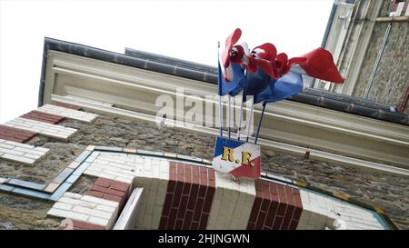 Ansicht von unten auf hängende Fahnen. Aktion. Flaggen hängen und schwingen über dem Bogen des bedeutenden Gebäudes der Stadt. Ansicht von unten auf verdrehte Hängefahnen. Stockfoto