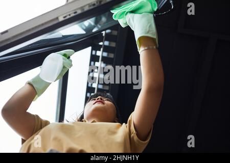 Low-Winkel-Porträt der jungen asiatischen Frau Reinigung Fenster zu Hause, kopieren Raum Stockfoto