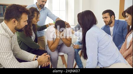 Menschen trösten und unterstützen den Mann, der während der Gruppentherapie weint Stockfoto