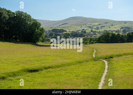 Ein Fußweg, der durch eine Wiese zu einer Brücke über den Fluss Ure bei Hawes in Wensleydale führt Stockfoto