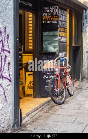 Rotes Fahrrad, das am frühen Morgen im Tempelbarbereich gegen die Wand gelehnt ist, berühmte irische Pubs, Stadt- und Straßenfotografie, Dublin, Irland Stockfoto