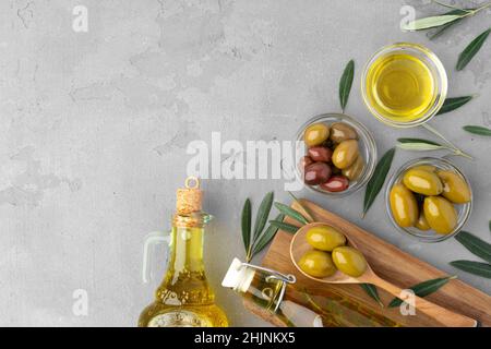 Flatlay Zusammensetzung aus Oliven und Olivenöl auf grauem Hintergrund Stockfoto