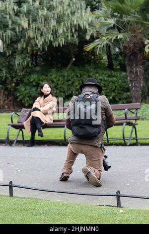 Die Fotografin macht ein Foto des Mädchens, das auf der Bank sitzt, St Stephen’s Green Park , Urban, Street Photography, Dublin, Irland Stockfoto